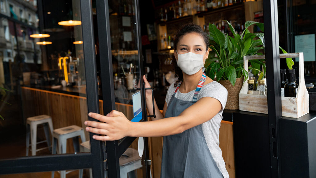 Happy Business Owner Opening The Door At A Cafe Wearing A Facemask