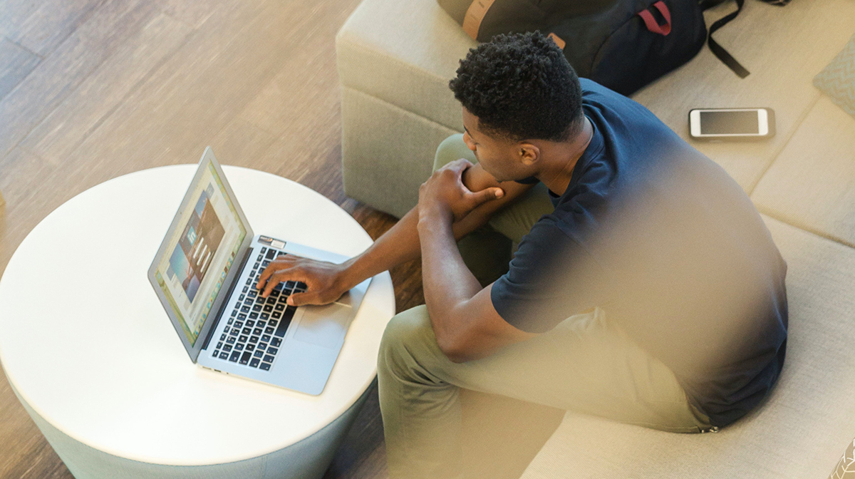 Aerial shot of man sitting on coach looking at laptop on coffee table