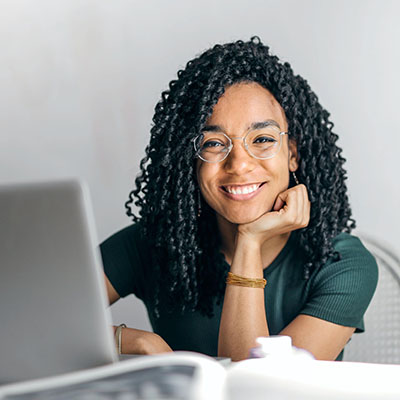 women sitting in front of computer looking into camera smiling